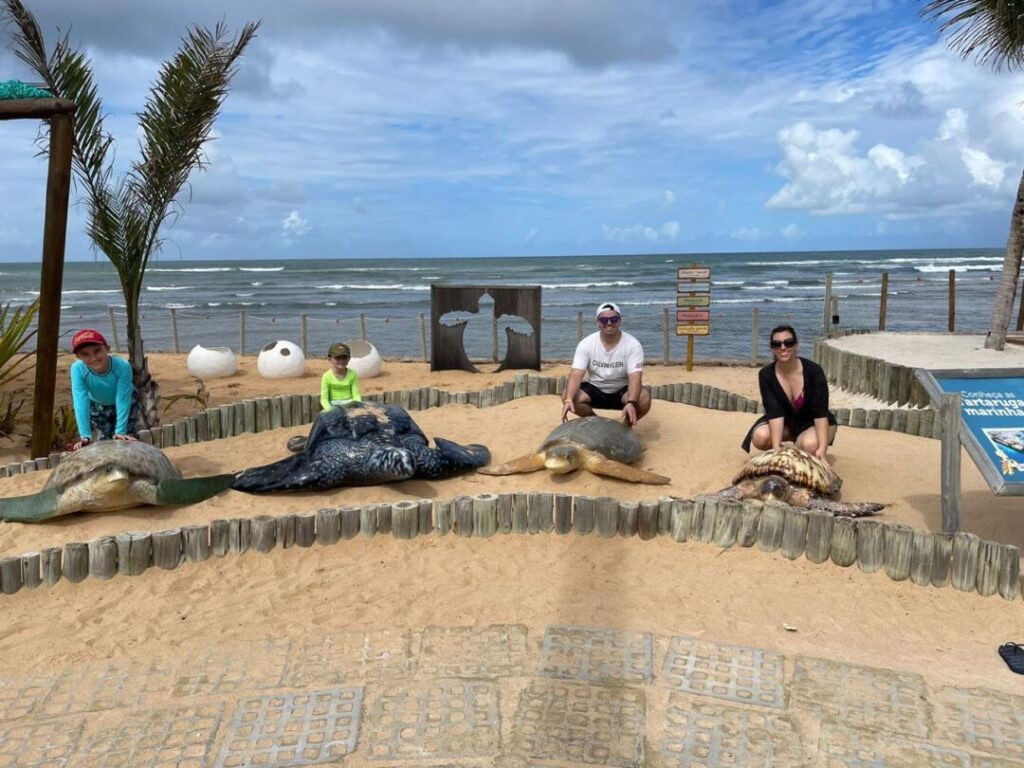 Família em praia com tartarugas cenográficas