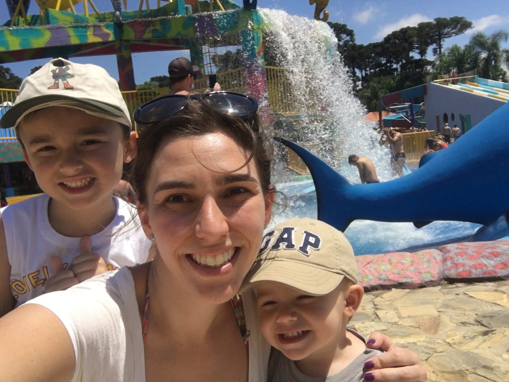 selfie de dois meninos com mãe e cachoeira de parque aquático ao fundo