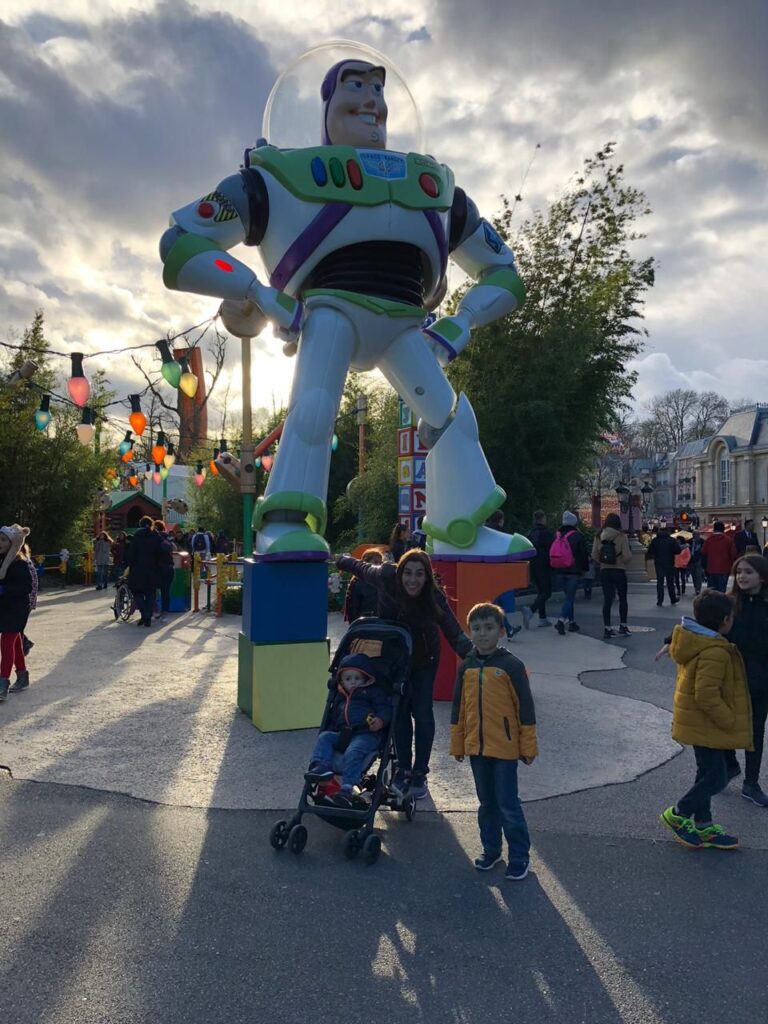 mãe e duas crianças em frente a grande estátua do personagem buzz lightear