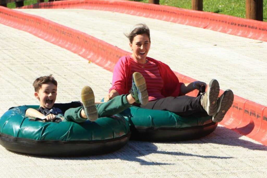 Mulher e menino descendo de tubing em parque temático