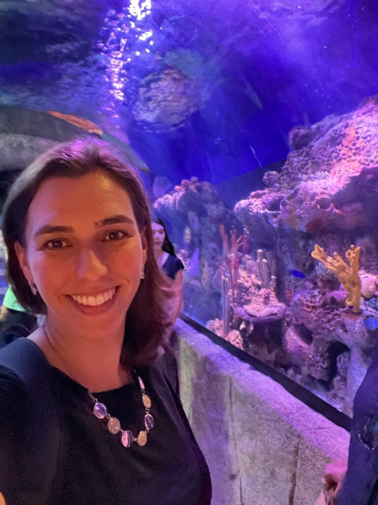 mulher sorrindo com grande aquário no fundo