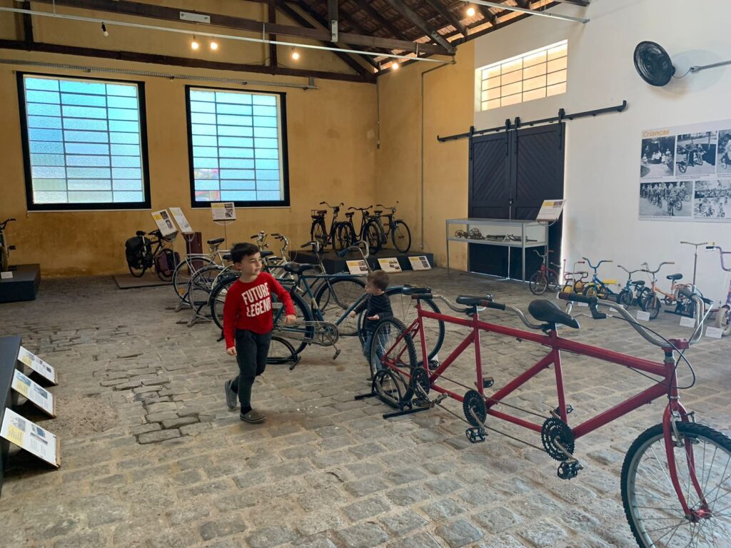 menino andando entre exposição de bicicletas antigas