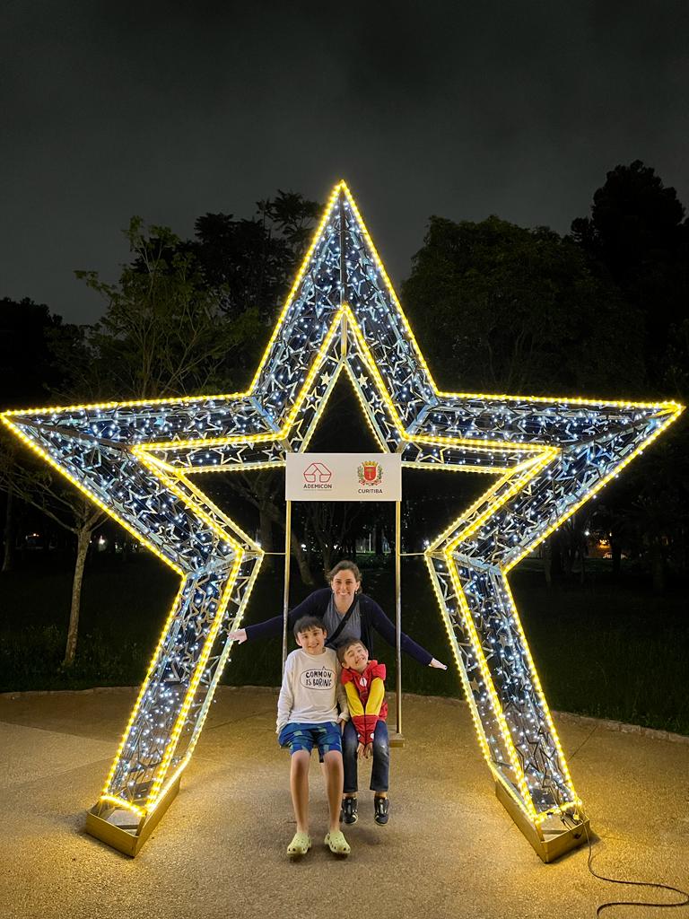 mãe e dois meninos no meio de grande decoração de estrela de natal