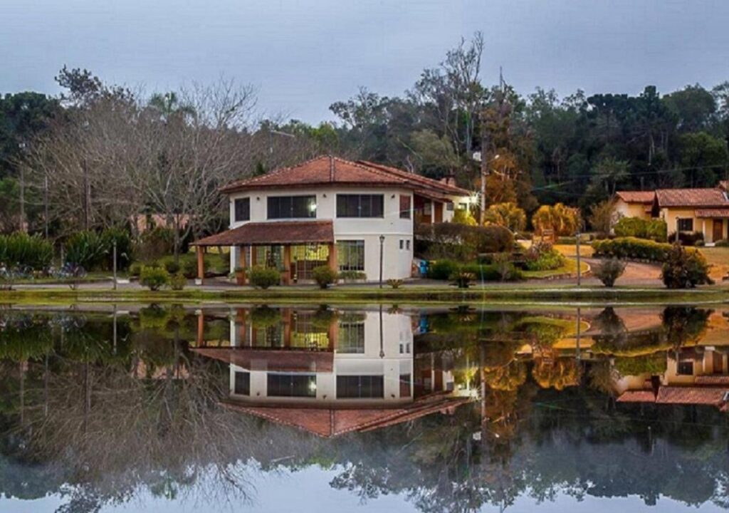 Casa com lago a frente fazendo reflexo da construção