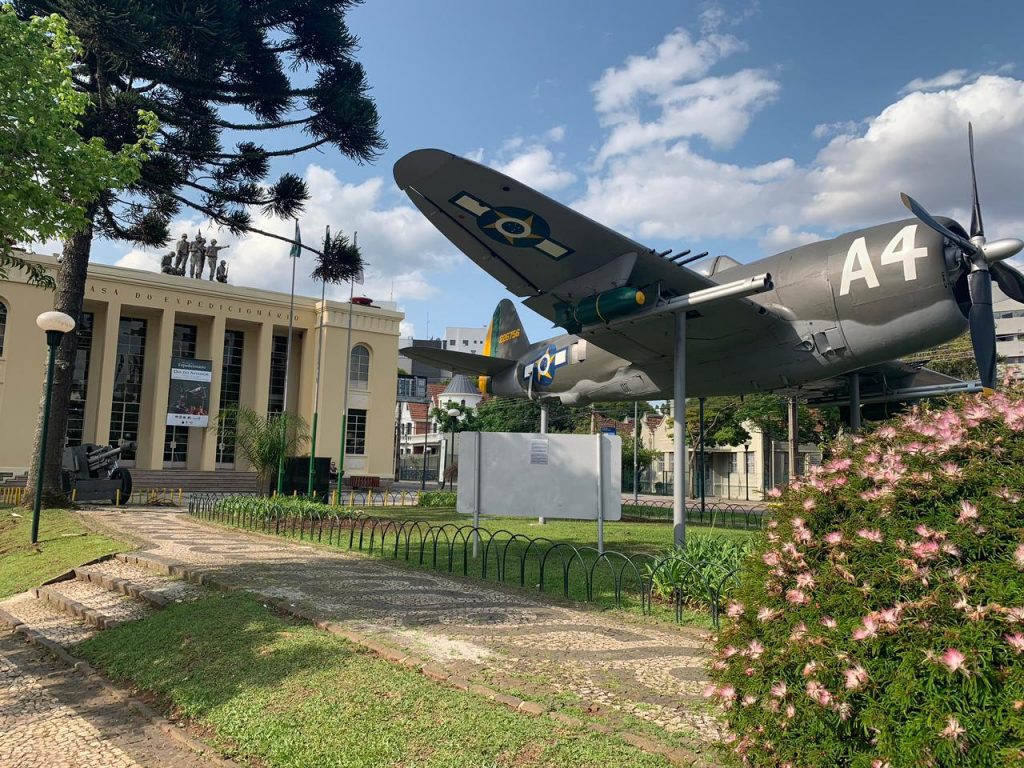 réplica de avião de guerra com museu ao fundo