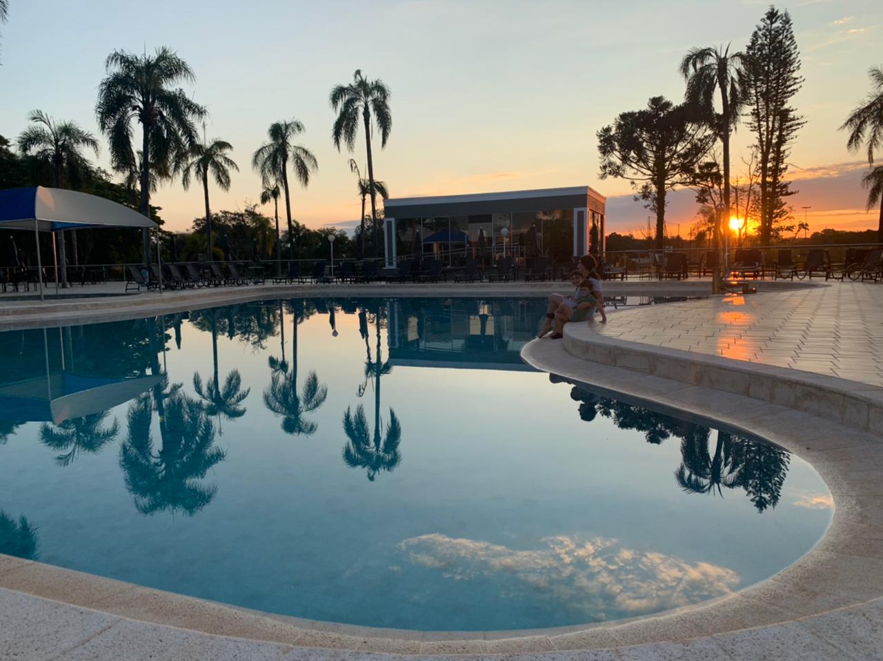 piscina grande com pôr do sol ao fundo