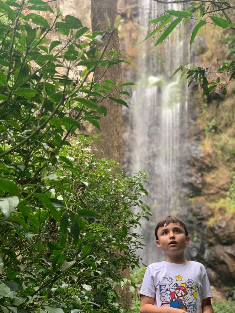 menino olhando para cima com cachoeira no fundo