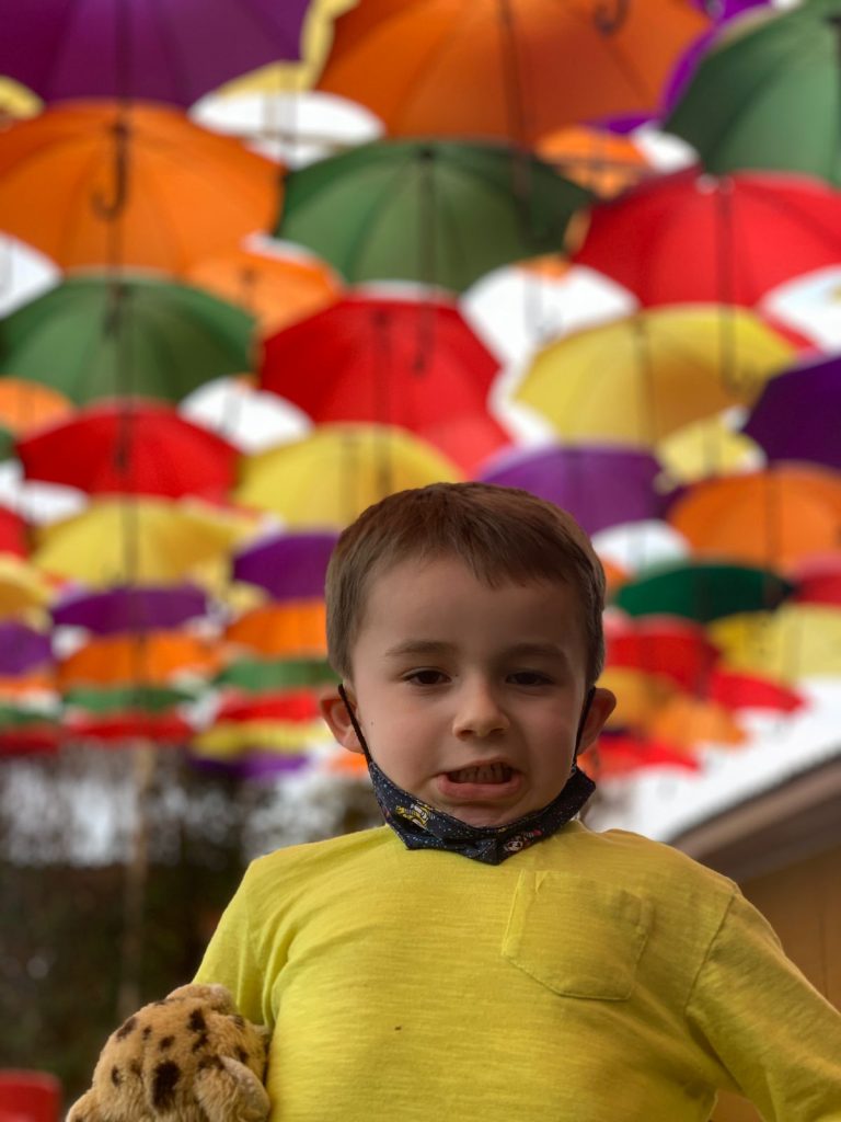 criança sorrindo em primeiro plano com guarda chuvas no fundo