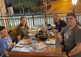Família com 4 pessoas sentada em mesa ao ar livre a noite