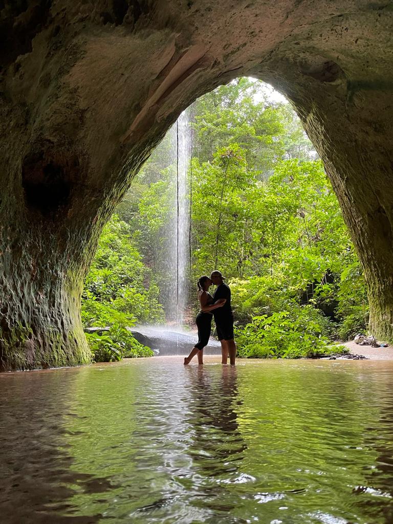Silhueta de casal se beijando na entrada de uma caverna