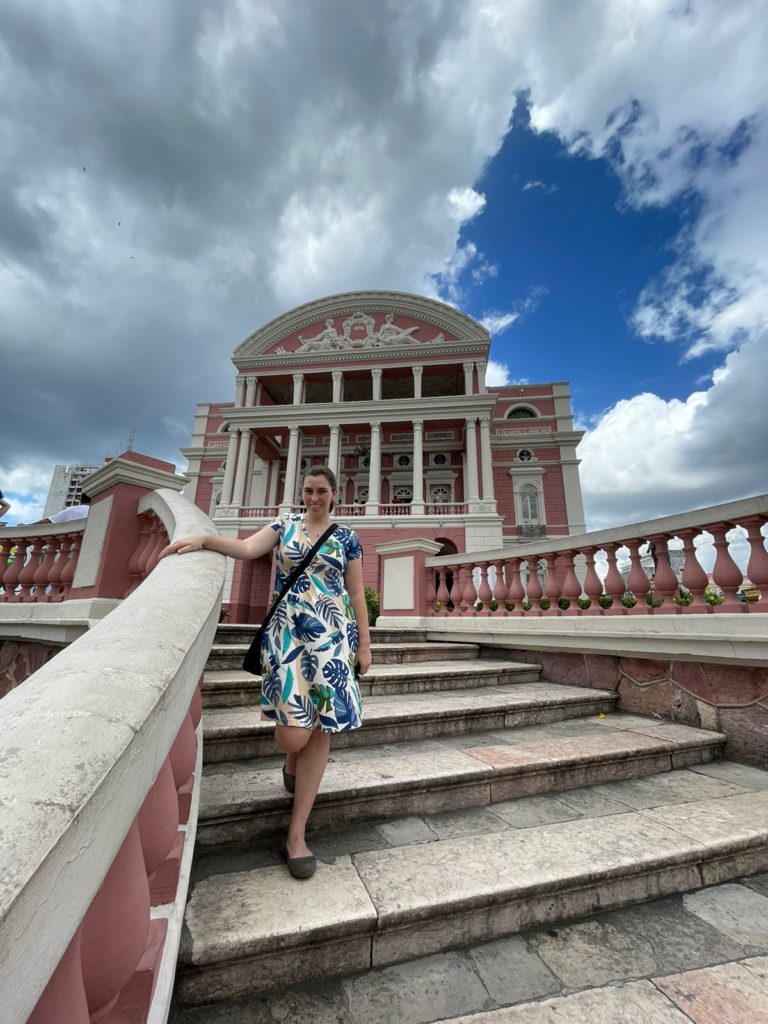mulher sorrinho em escada na frente da fachada do teatro histórico 
