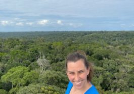 Mulher sorrindo em mirante com floresta amazônica ao fundo