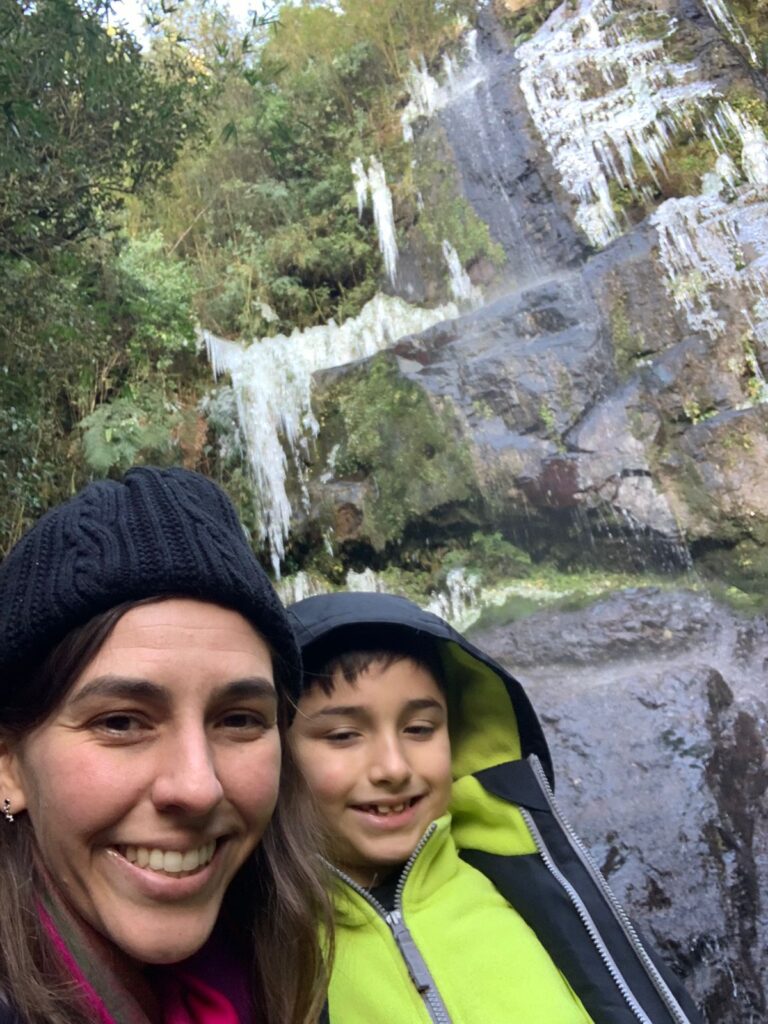 selfie mãe e filho pequeno com cascata congelada com cristais de gelo