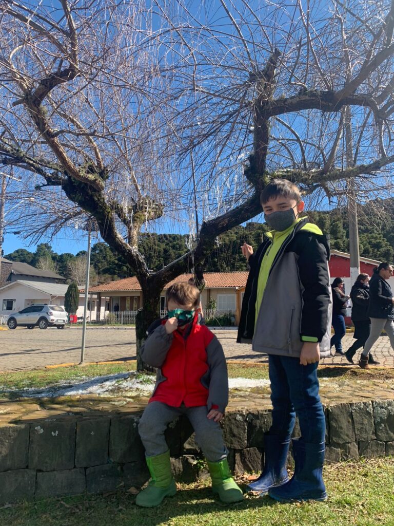 dois meninos de 4 e 7 anos em frente a árvore com cristais de gelo