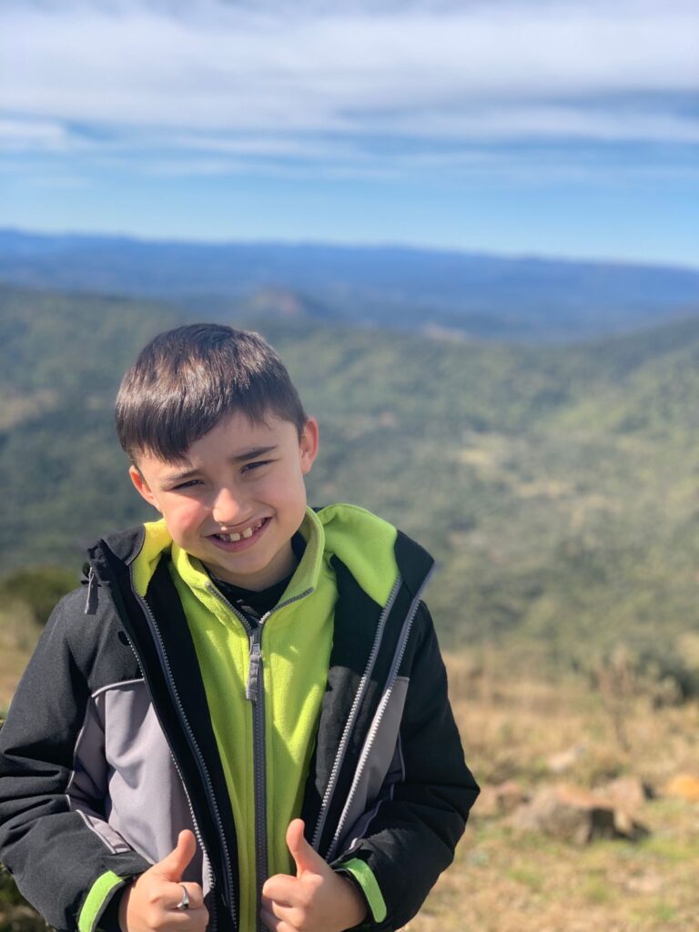 menino sorrindo com vista de montanhas ao fundo