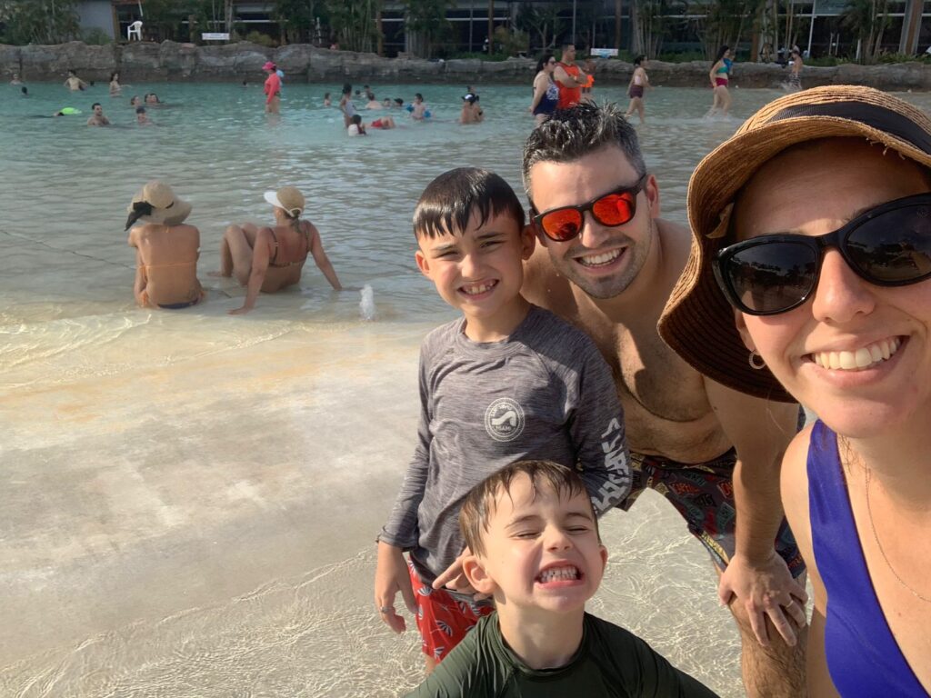 Selfie de familia (mae, pai e dois meninos) com piscina ao fundo