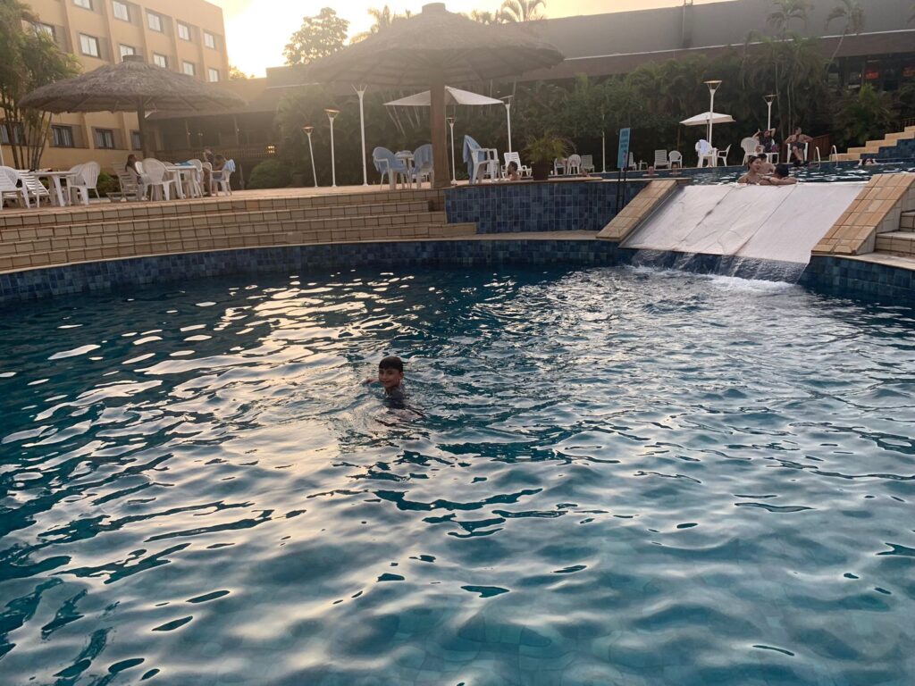 menino nadando em piscina no pôr do sol