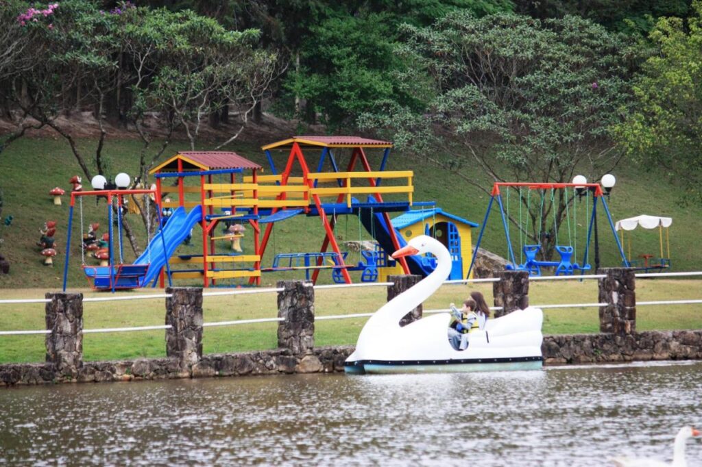 Parque infantil ao fundo com pedalinho de cisne em lado a frente