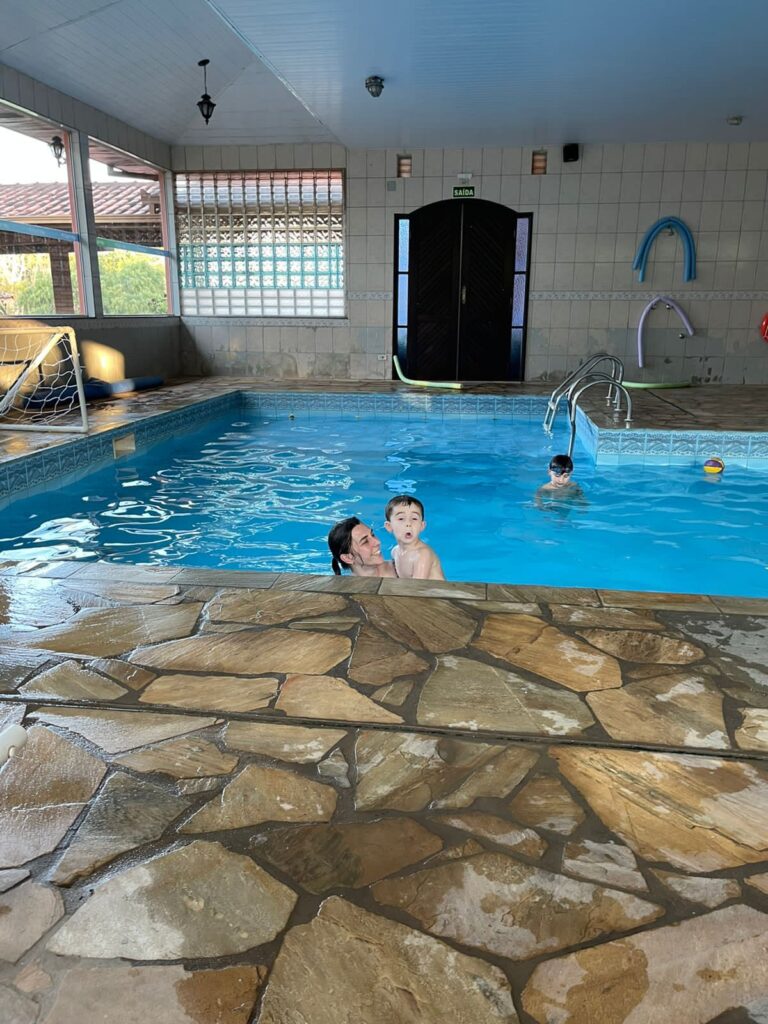 mãe e filho dentro de piscina coberta