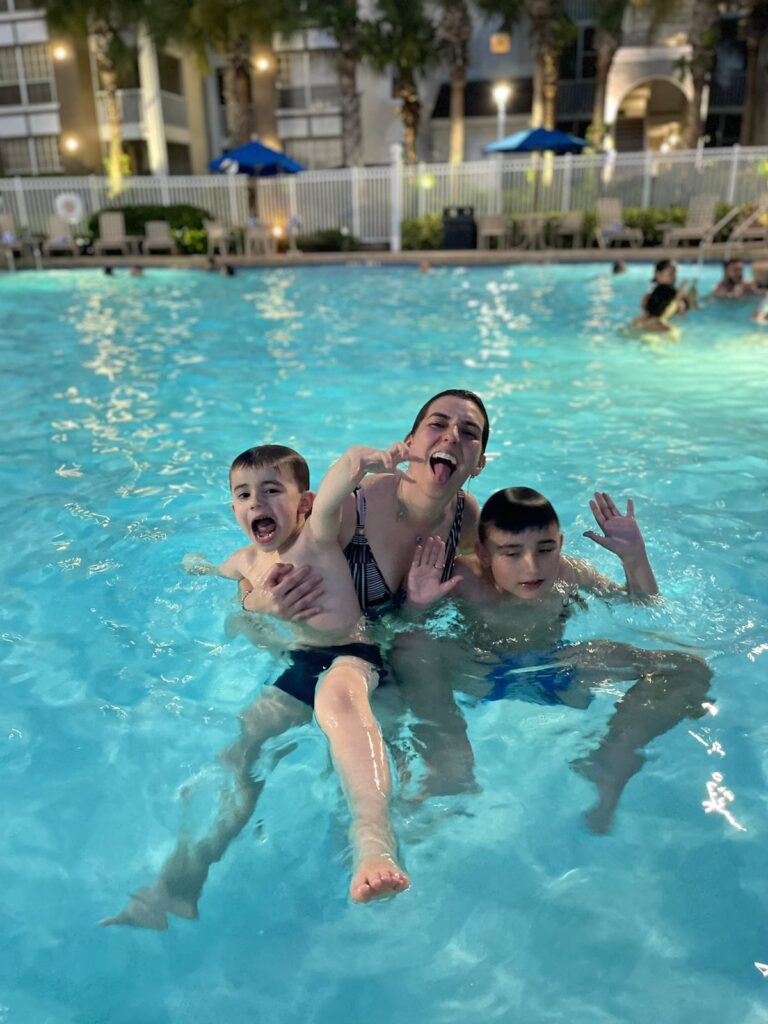 mãe e dois meninos na piscina fazendo caretas