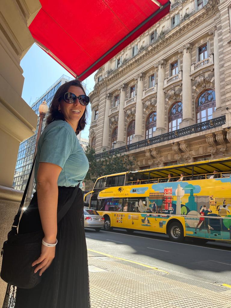 mulher olhando para atrás com ônibus turístico passando ao fundo