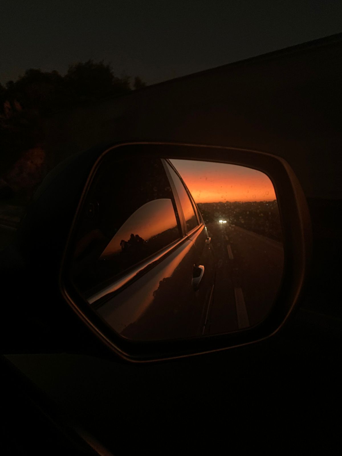 retrovisor de carro refletindo nascer do sol na estrada
