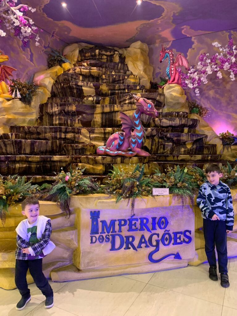 Dois meninos em frente a fonte de chocolate temática de dragões