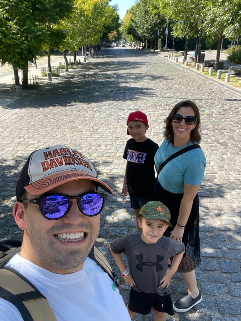 Selfie de pai, mãe e dois filhos em rua charmosa de paralelepípedo
