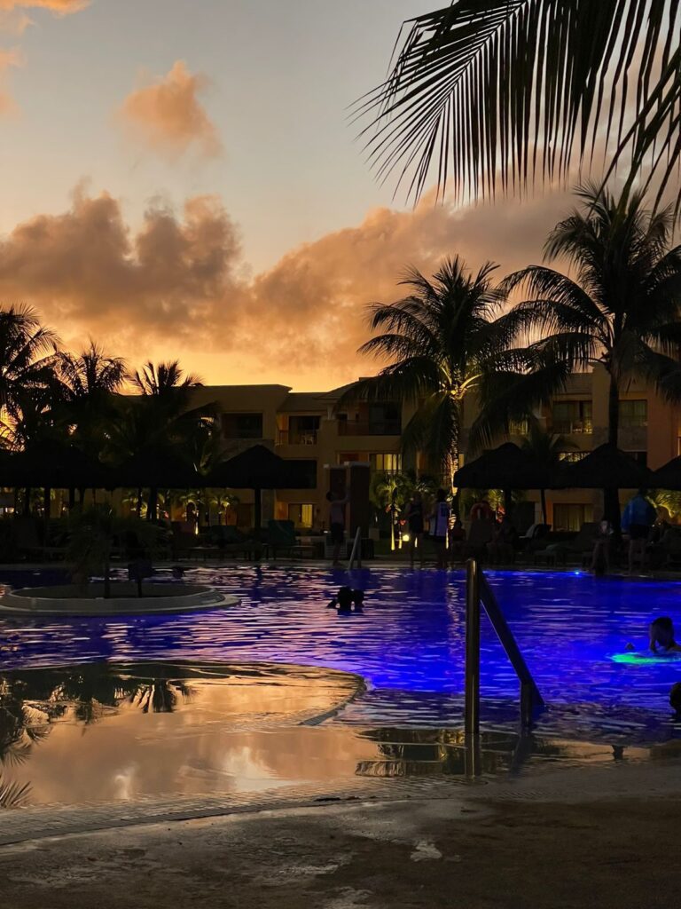 pôr do sol em piscina com hotel ao fundo