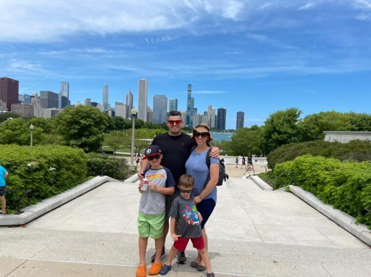 pai, mãe e dois meninos em parque com skyline de chicago no fundo