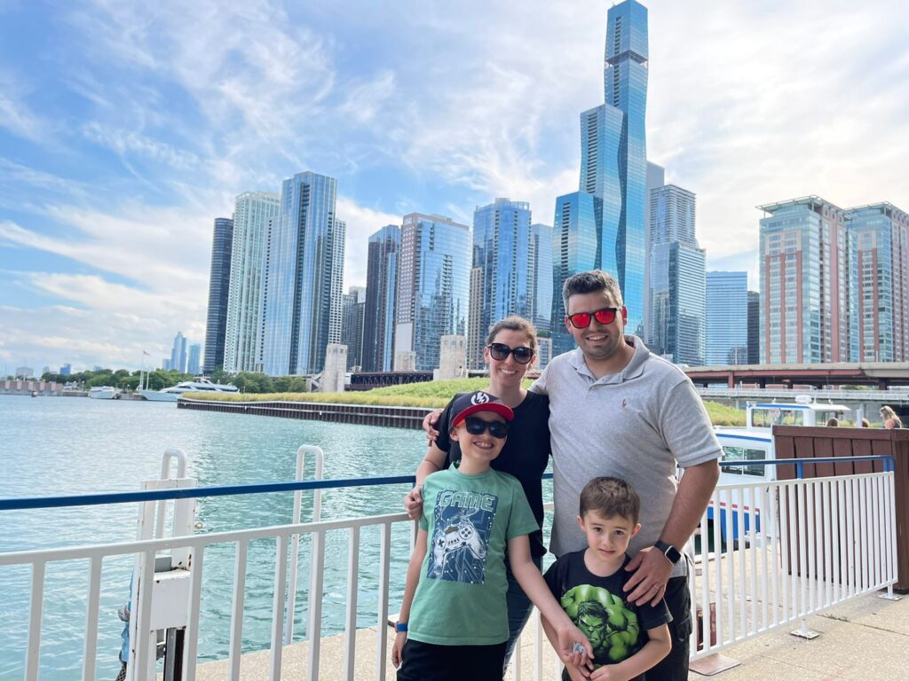 familia de mae, pai e dois meninos com lago michigan e skyline de chicago ao fundo