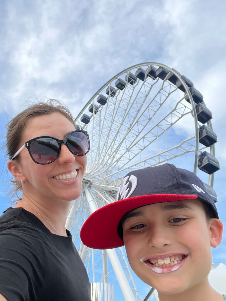 mulher e menino sorrindo em selfie com roda gigante ao fundo