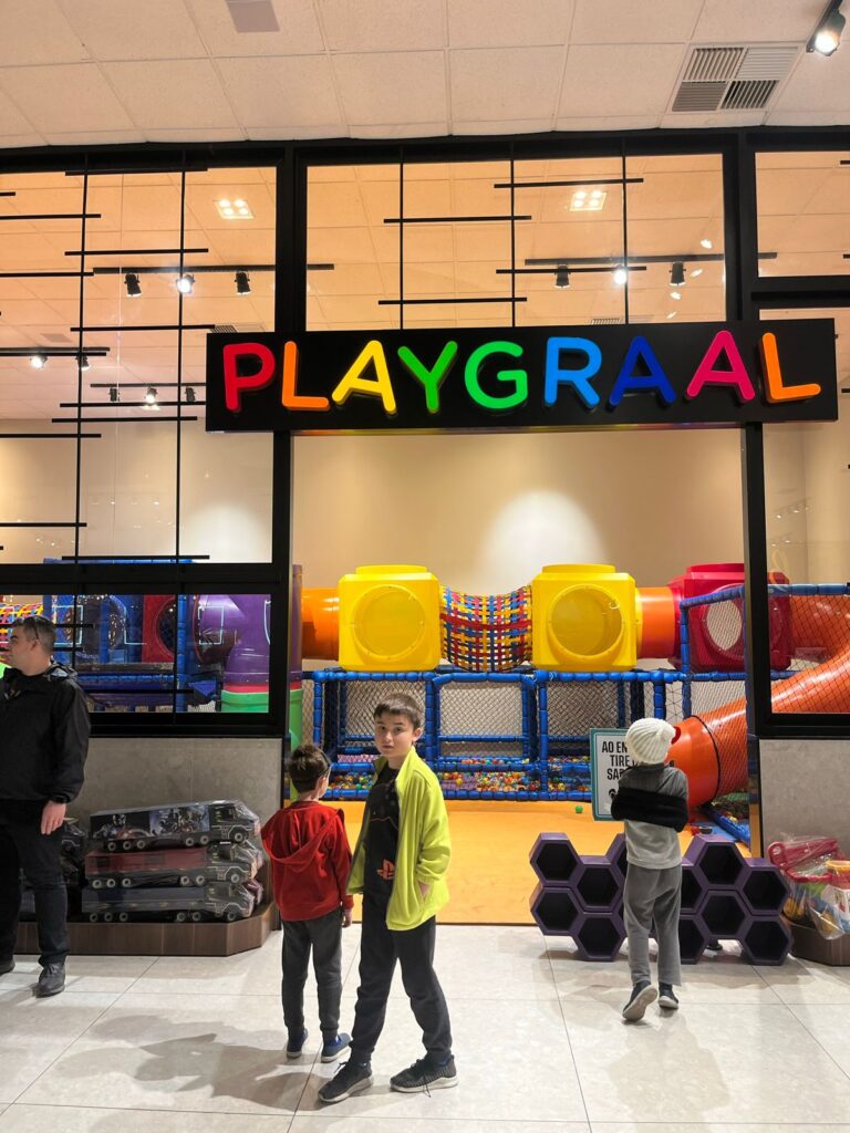 dois meninos em frente a entrada de espaço kids com brinquedão e escorregador
