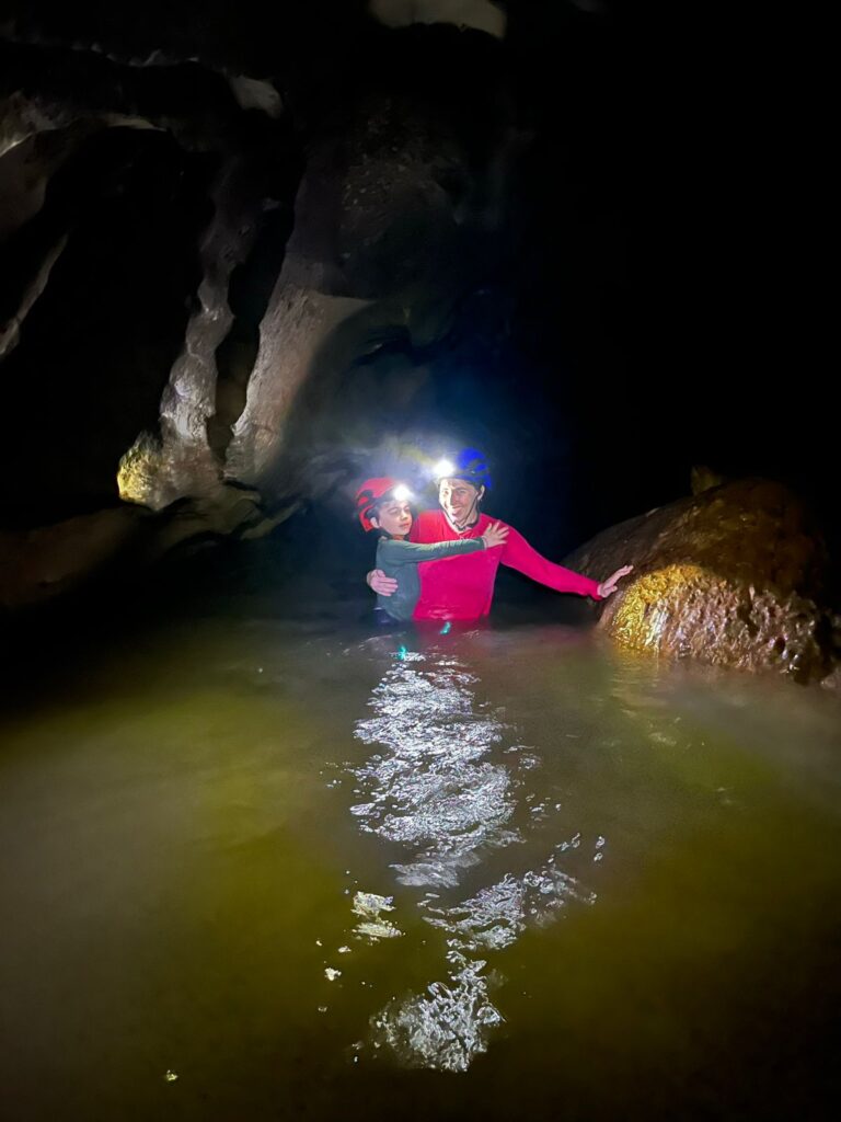 mãe segurando menino dentro de rio na caverna