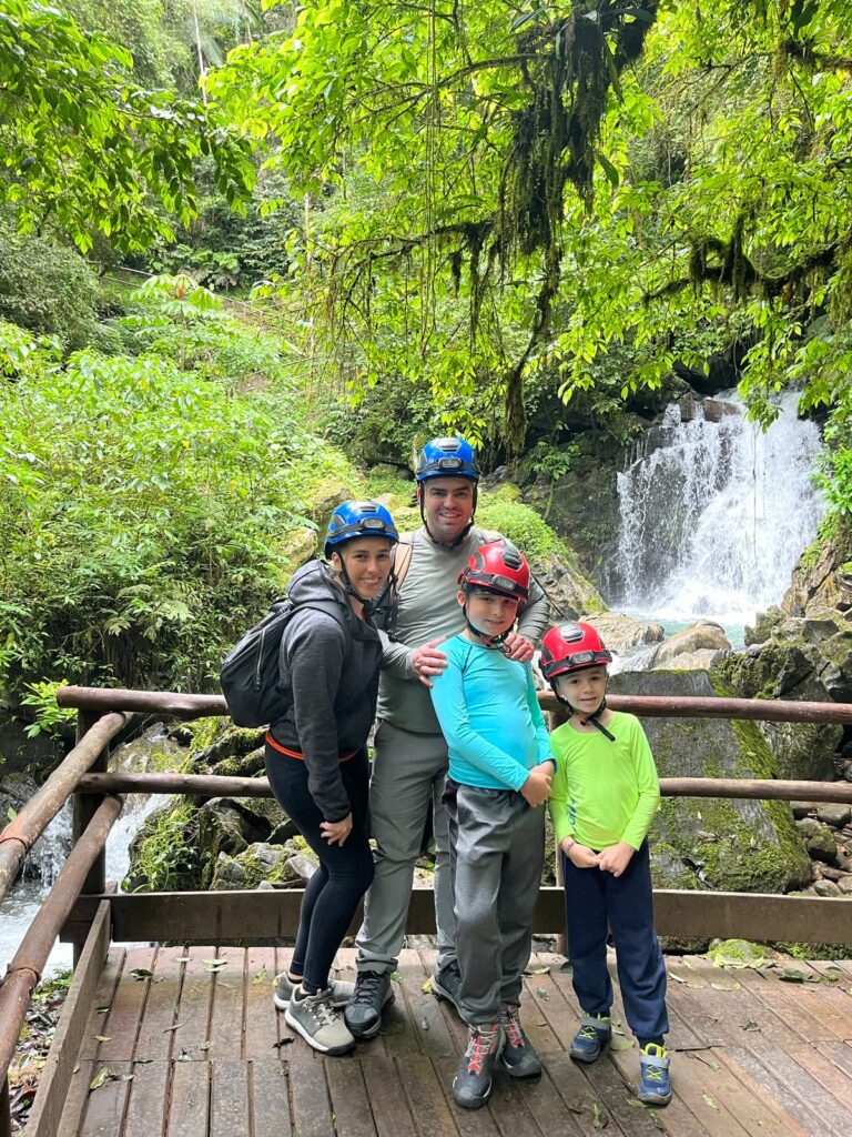 pai, mãe e dois meninos em frente a cachoeira