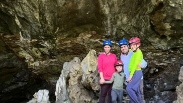 familia de mãe, pai e dois meninos em entrada de grande caverna