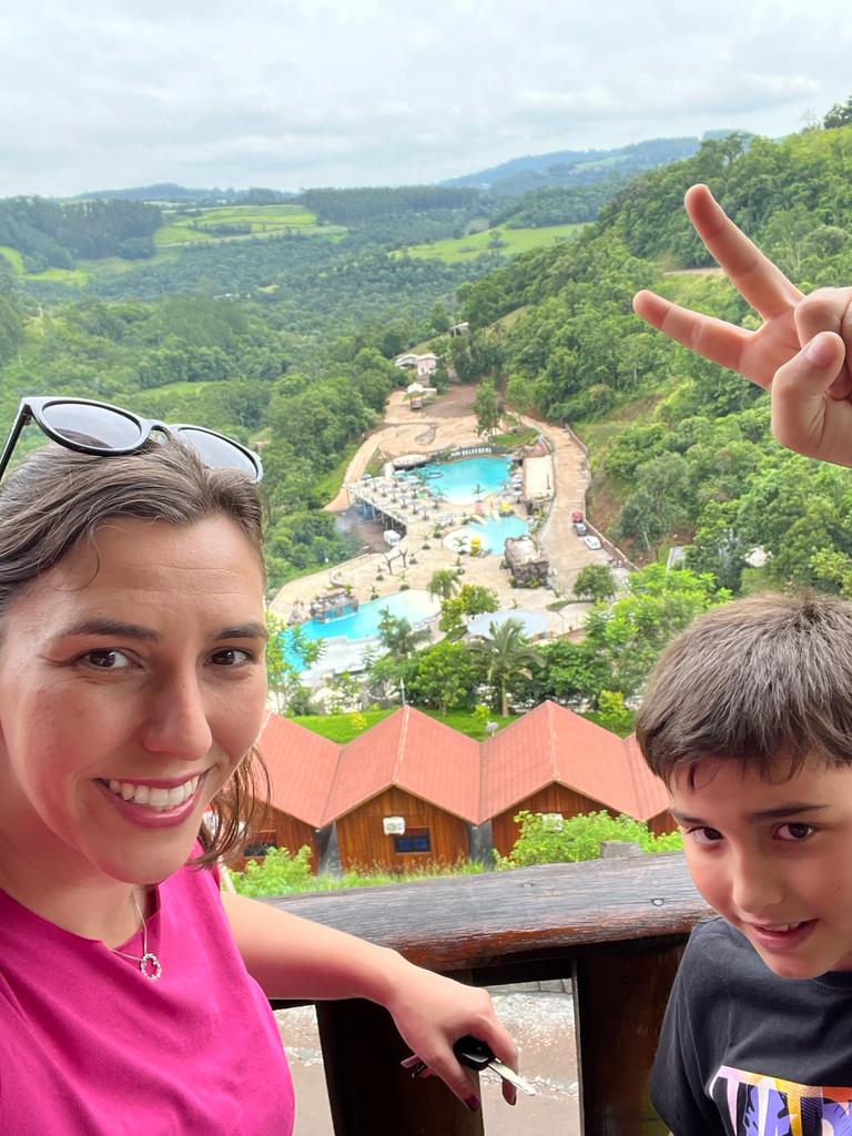 selfie de mulher e menino com vista do alto de um complexo de piscinas