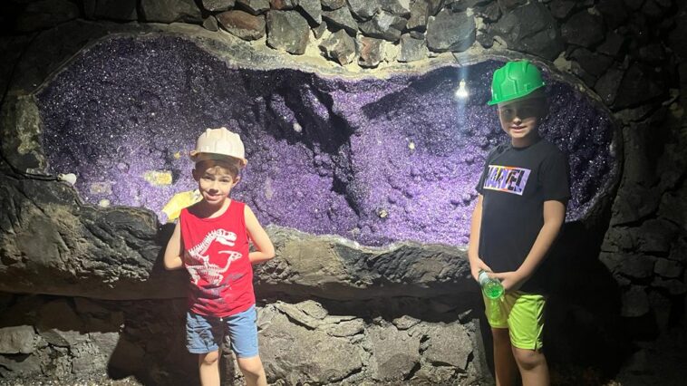 dois meninos dentro de mina em frente a grande pedra ametista