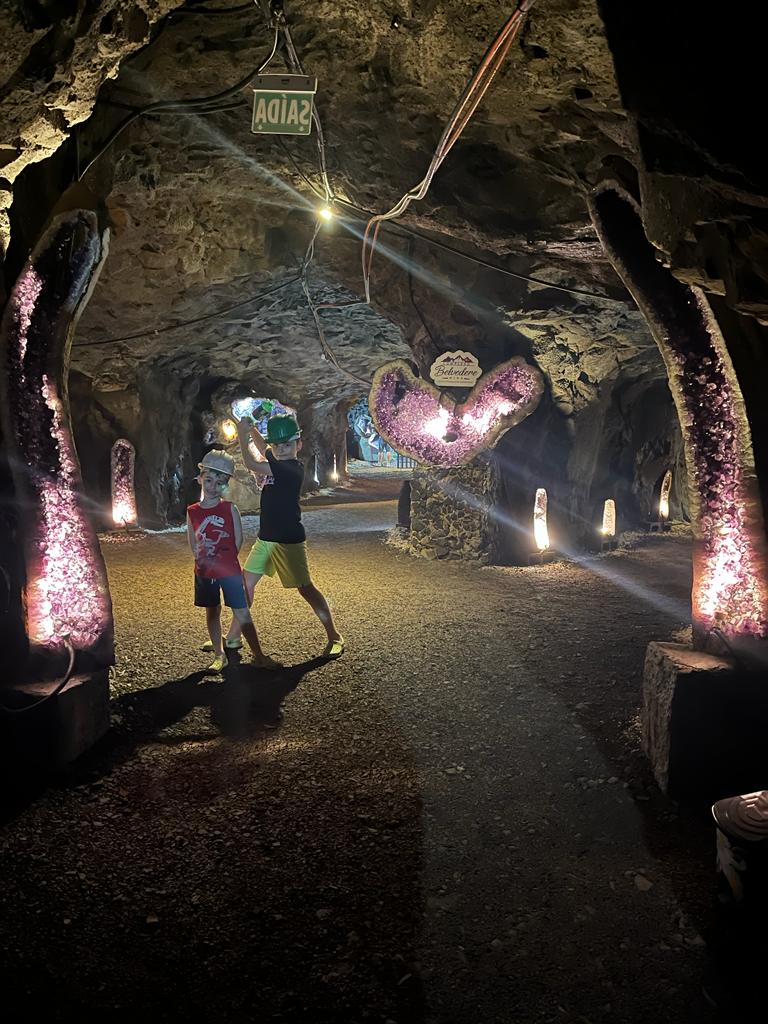 dois meninos dentro de uma mina com diversas pedras preciosas ao fundo