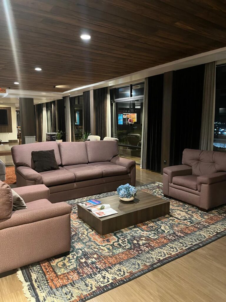 área de estar de hotel com 3 sofás e mesa de centro
