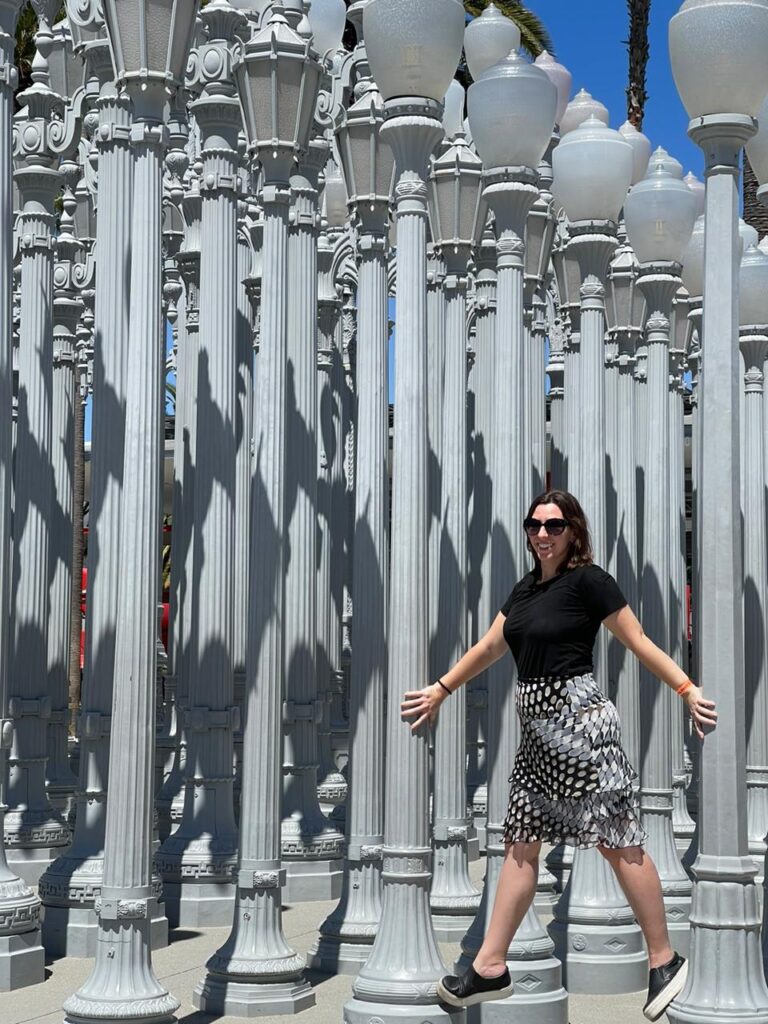 mulher em frente a obra de arte com postes de luz diversos