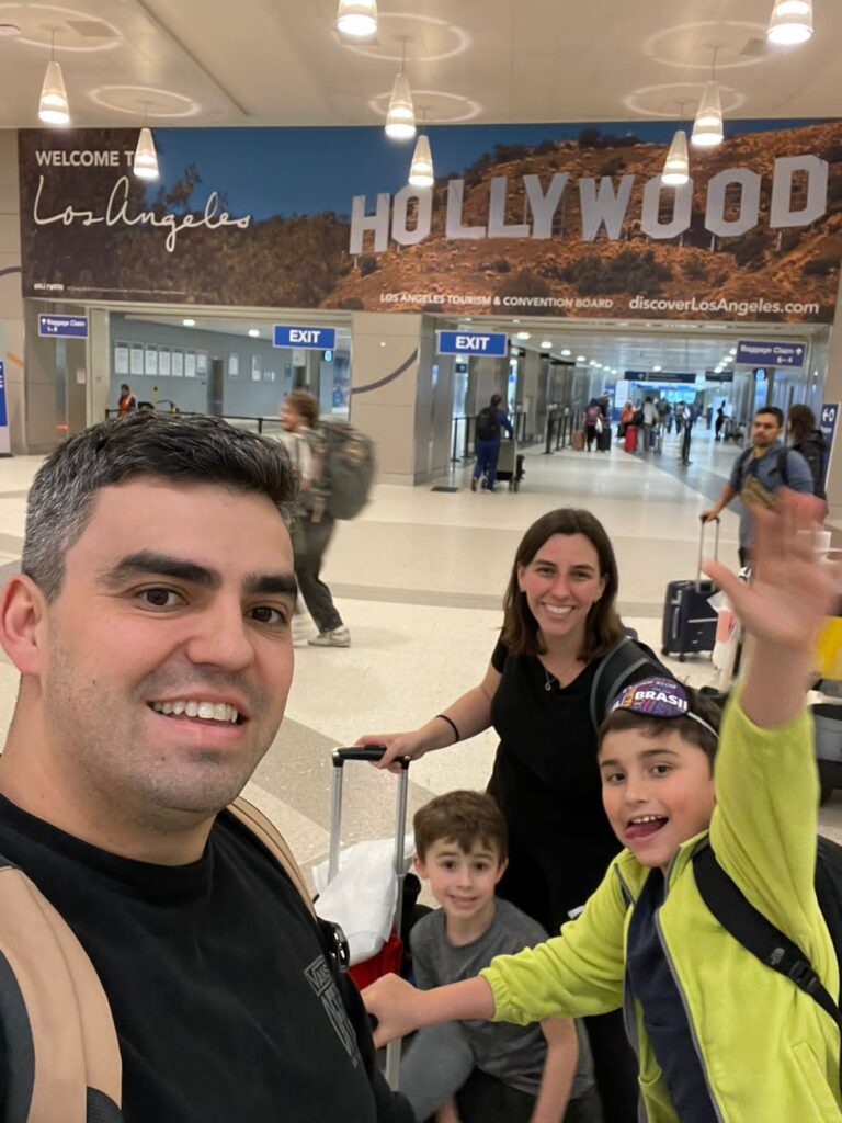 familia em aeroporto com cartaz atrás de hollywood