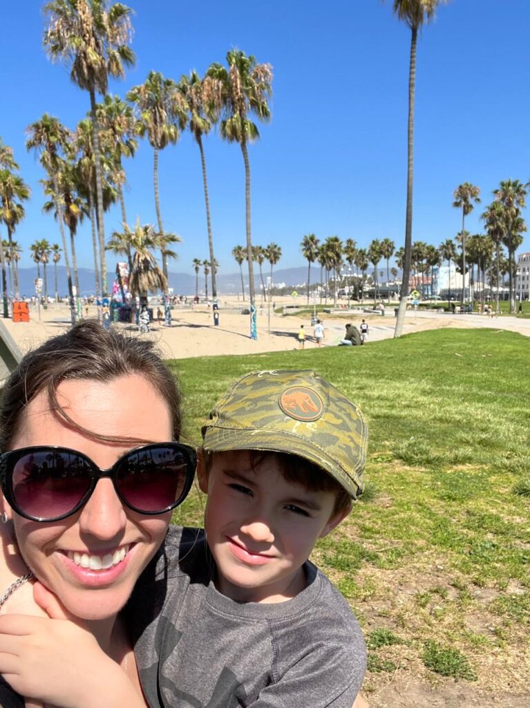selfie de mãe e menino com praia e palmeiras ao fundo