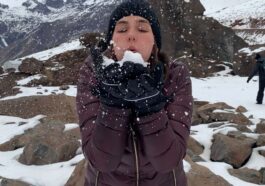 mulher assoprando neve entre montanhas