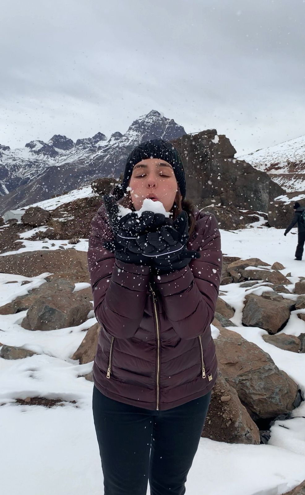 mulher assoprando neve entre montanhas