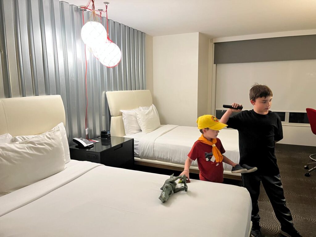 dois meninos dentro de quarto de hotel com duas camas