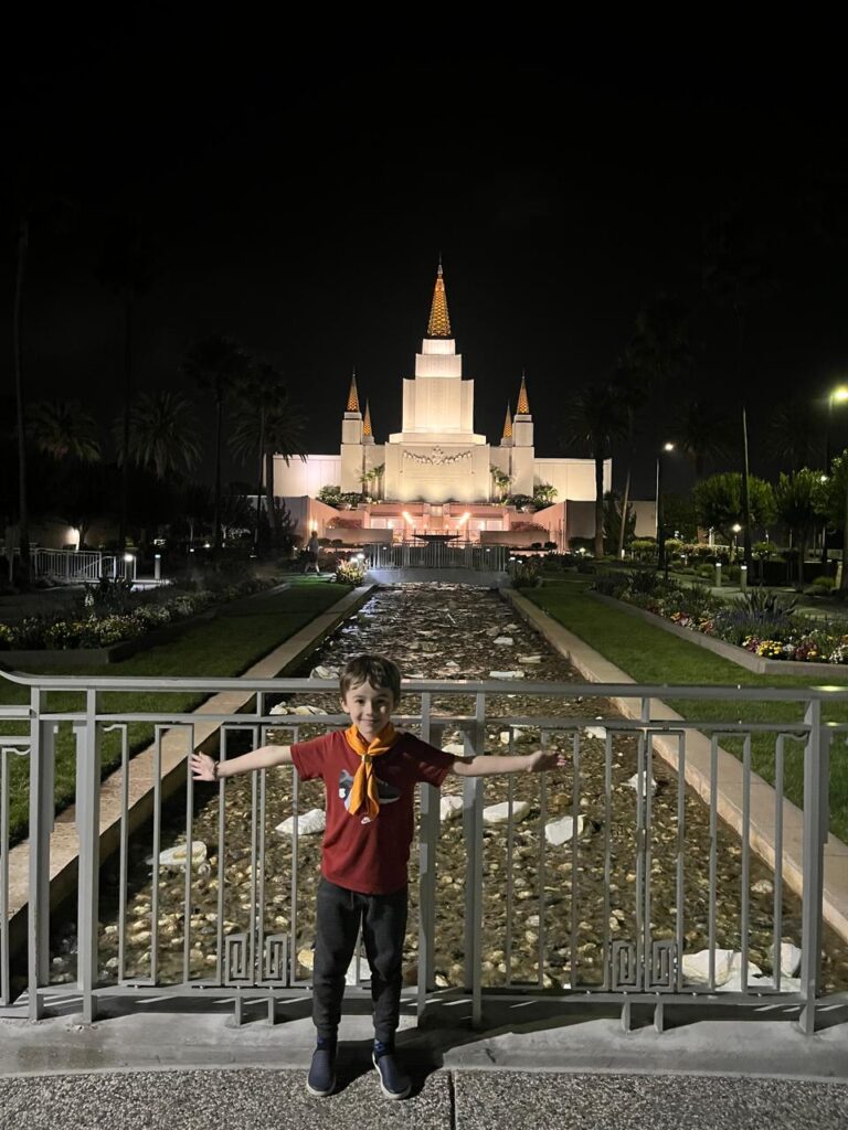 menino de braços abertos em frente a templo a noite