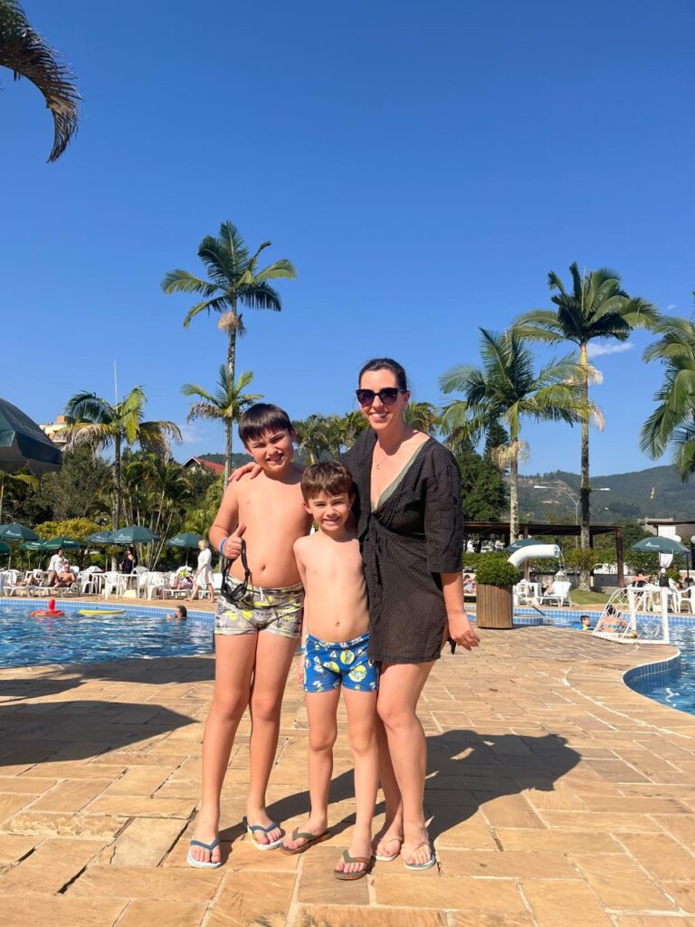 mãe dois filhos em área de piscinas de hotel