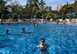 menino dentro de grande piscina de hotel