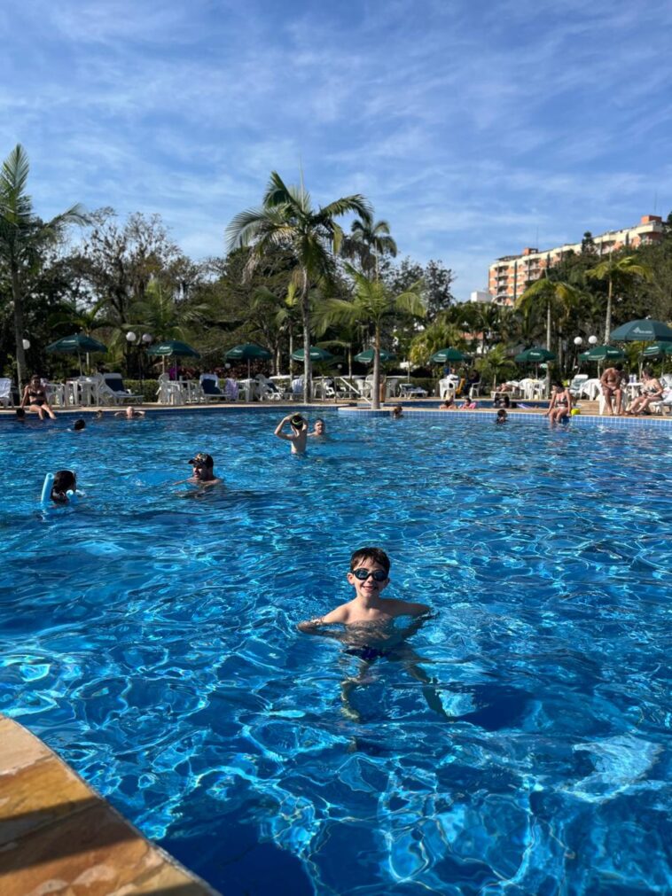 menino dentro de grande piscina de hotel